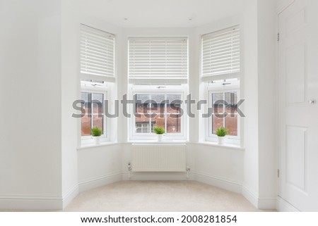 An empty modern room in an urban apartment with plain white walls and bay window in the UK Royalty-Free Stock Photo #2008281854