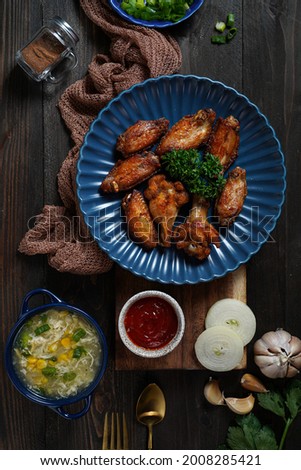 Chicken wings and broccoli corn soup prepared on black wood table. Food photography, low light food photography. 