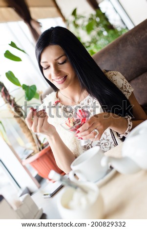 picture of young happy smiling woman beautiful brunette girl having fun eating ice cream in coffee shop or restaurant interior copy space background portrait