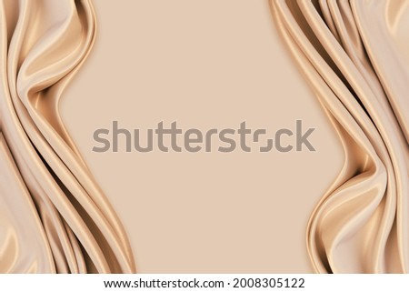 Beautiful elegant wavy light brown or beige satin silk luxury cloth fabric texture with monochrome background design. Copy space