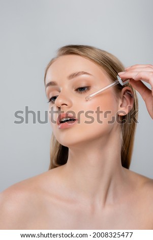 pretty woman applying serum with pipette isolated on grey Royalty-Free Stock Photo #2008325477