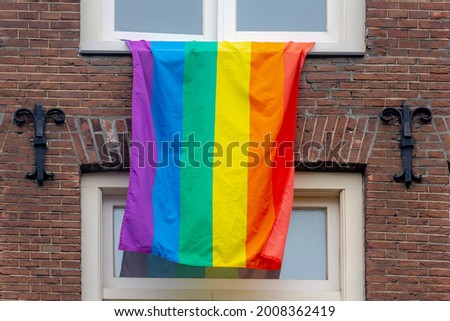 Celebration of Pride month, Colourful rainbow flag hanging outside  the window of building, The symbol of lesbian, gay, bisexual and transgender, LGBTQ community in Amsterdam, Netherlands.