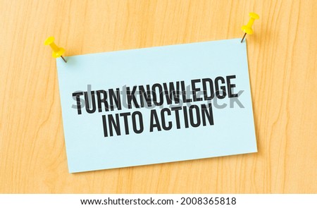 Turn Knowledge Into Action sign written on sticky note pinned on wooden wall