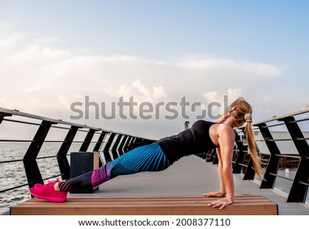 Young woman doing sports exercises at dawn near the ocean.