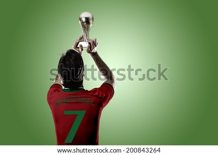 Portuguese soccer player, celebrating the championship with a trophy in his hand. On a green background.