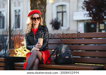 Cheerful stylish young woman in the street drinking morning coffee in sunshine light.