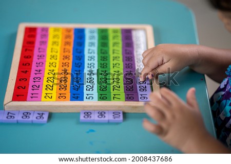 Little girl learning numbers on magnet board at table at home.
