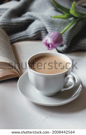 Spring composition flat lay with white  cup of coffee, bouquet of violet tulips, old book, concept of spring and comfort. Women’s day card, poster, banner, wallpaper. Still life morning photo.