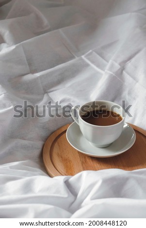 White coffee cup on bed. Cozy autumn morning photography. Still life concept. White fabric background. 