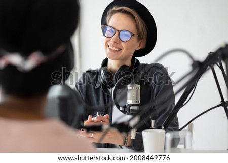 Young and confident European woman recording a podcast in a recording studio, woman creating audio content or recording radio interviews, business woman radio host recording commercials or