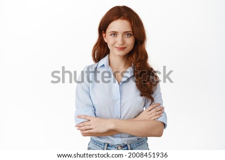 Confident young business woman professional, cross arms on chest and smiling determined, standing in office blouse against white background, staring ready