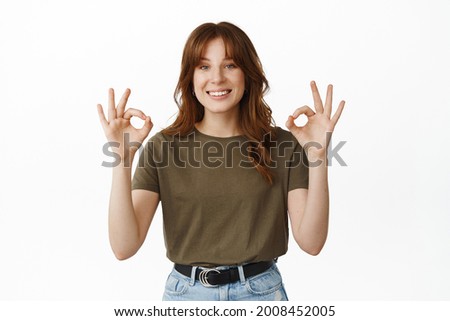 Very well, good job. Smiling young woman showing Okay ok gesture, nod in approval, say yes, agree with your choice, praise great thing, standing over white background