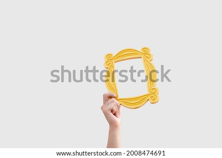 a hand holds a yellow frame from the TV series friends Royalty-Free Stock Photo #2008474691