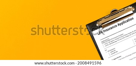 Life insurance form. Clipboard with insurance policy and agreement on a bright yello desktop backgrond. Banner, copy space and top view 