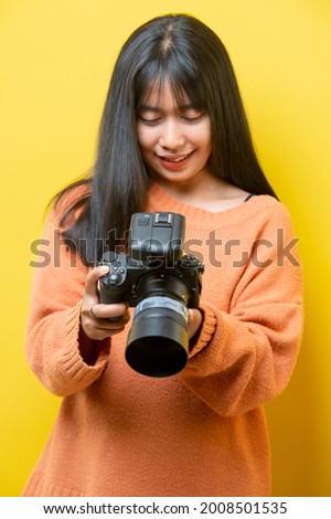 Portrait of a surprise girl with a camera in hand on a yellow background. Isolated studio. 