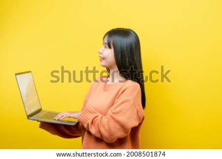 Full length body size turned photo of cheerful positive cute nice attractive blogger browsing through her laptop in search of new information isolated over yellow vibrant color background