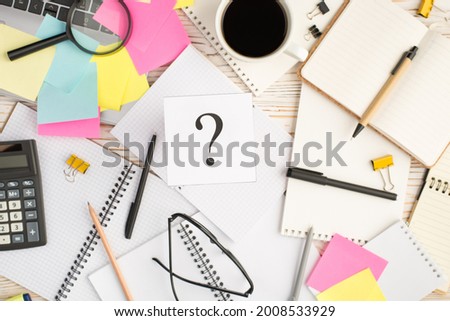Top view photo of multicolor sticker notes with interrogation mark laptop cup of coffee binder clips magnifier spectacles organizers pens pencil and calculator on isolated bright wooden background