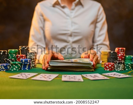 Cards and chips are laid out on a green gambling table. A croupier in a white shirt is getting ready to play. Gambling, hobbies, gambling addiction. Close-up. Careful viewing.