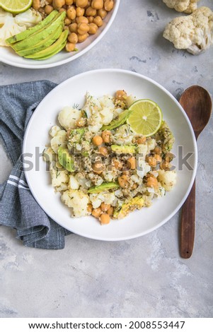A bowl of healthy vegan and vegetarian lunch or dinner. Salad of fried chickpeas, quinoa, avocado, cauliflower on a light background.Top view, flat lay