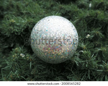 a large gray round ball is hanging on a green Christmas tree . bottom view