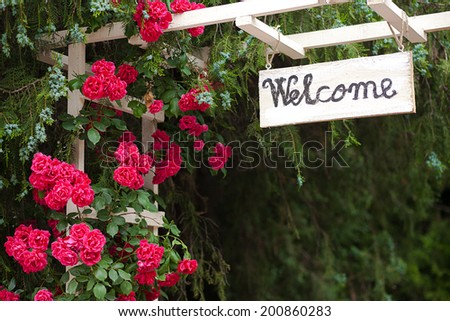 Red flowers and welcome wood panel at hotel entrance