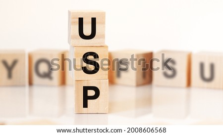wooden cubes with letters USP arranged in a vertical pyramid, on the light background, reflection surface, business concept. USP short for unique selling proposition
