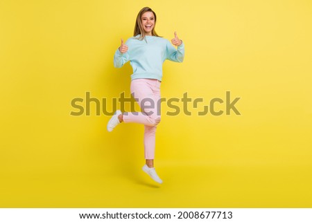 Full length body size view of attractive cheerful girl jumping showing thumbup ad isolated over bright yellow color background