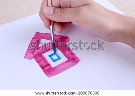 Child draws house with watercolors, close up