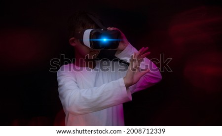 Asian young boy wearing virtual reality VR to play game graphic,amazing futuristic space virtual imaging with black background .