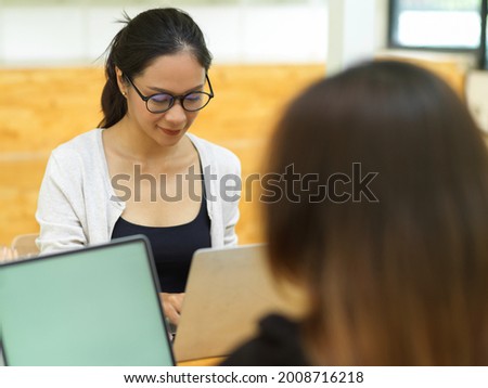 Businesswoman working with her laptop at office with co-worker, female college doing group works on laptop with her friend at campus