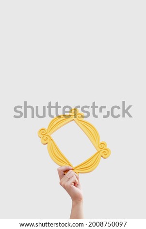 a hand holds a yellow frame from the TV series friends Royalty-Free Stock Photo #2008750097