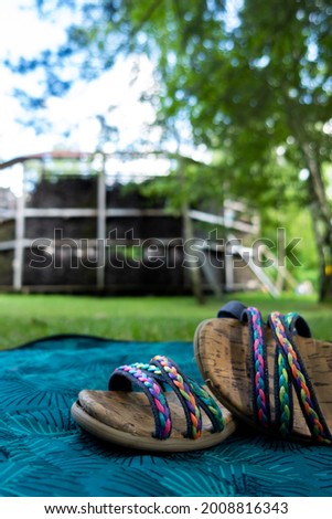 Colorful children's sandals stacked on a blanket in a city park. Picture taken in the shade under soft natural light.