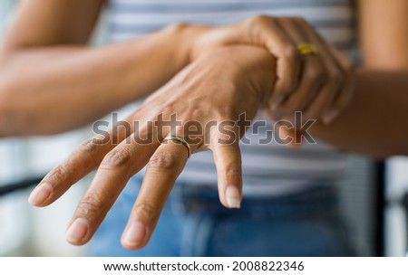 Woman in using hand to hold wrist and stretching fingers
 with feeling pain, suffer, hurt and tingling. Concept of Guillain barre syndrome and numb hands disease.