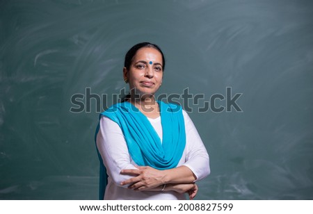 portrait of confident Indian teacher standing in front of the black board in class room Royalty-Free Stock Photo #2008827599