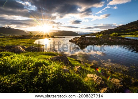 Scenic view of fjord landscape in northern norway with warm midnight sun in late spring with green grass and nature Royalty-Free Stock Photo #2008827914