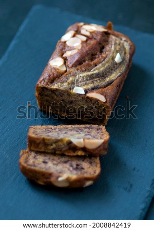Banana cake topping with almond slice on dark background
