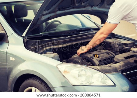 transportation and vehicle concept - man opening car bonnet and looking under hood Royalty-Free Stock Photo #200884571