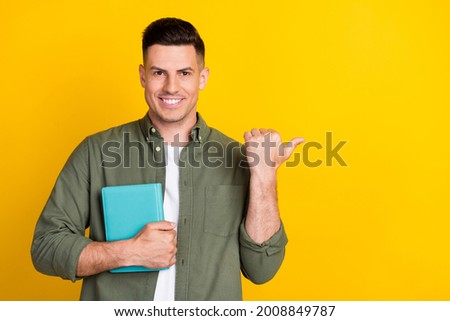 Photo portrait man smiling keeping book showing thumb isolated blank space vibrant yellow color background