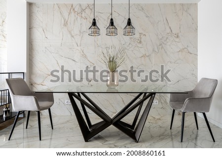 Stylish dining room with marble tiles on wall and floor and big, modern glass table with two chairs Royalty-Free Stock Photo #2008860161