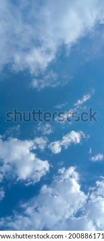 Cloudy blue sky background, vertical picture. Beautiful blue sky with tiny and soft fluffy clouds after raining. Elegant cloudy blue sky wallpaper background. Vertical image. Texture background