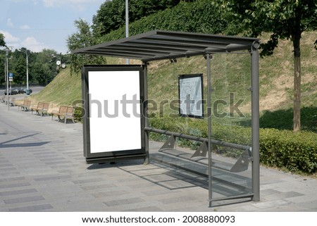 Blank billboard in the city center at a bus stop next to the road