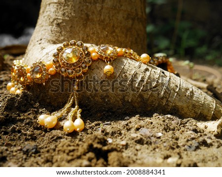 Gold necklace presented with tree roots at soil field, woman lifestyle product natural presentation