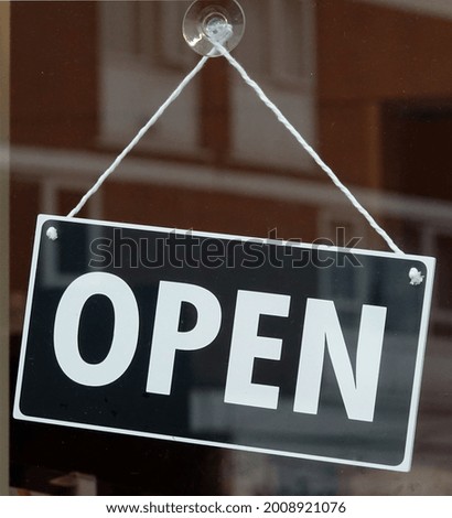 A closeup shot of an "Open" sign hanging from a glass door