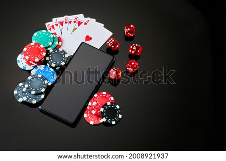 Casino chips, playing cards, dices and mobile phone on dark reflective background
