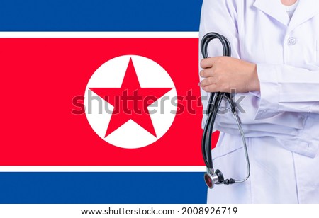 Female doctor with stethoscope in hand on the background of the North Korea flag. Concept medicine, pandemic in the country