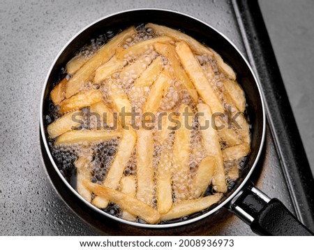 Close up of Frying french fries in the fryer in hot oil on the electric stove in the kitchen. Making homemade french fries. Royalty-Free Stock Photo #2008936973