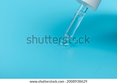 Cosmetic or medical glass bottle with pipette on blue background, in close-up. Skin care concept. 