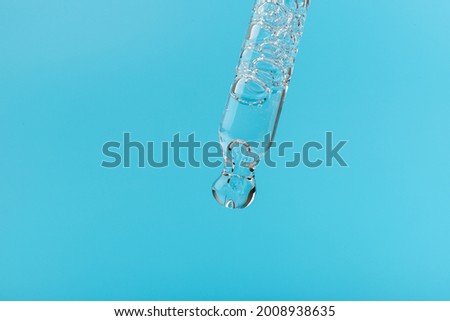 Cosmetic or medical glass bottle with pipette on blue background, in close-up. Skin care concept. 