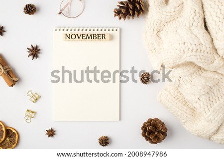Top view photo of white scarf organizer with inscription november pine cones dried lemon slices cinnamon sticks golden binder clips and stylish glasses on isolated white background with blank space