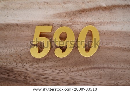 Gold numerals 590 on a dark brown to off-white wood pattern background.